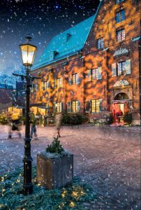 Kronhusgården och Kronhusets röda tegelfasad lyser upp samtidigt som det snöar.