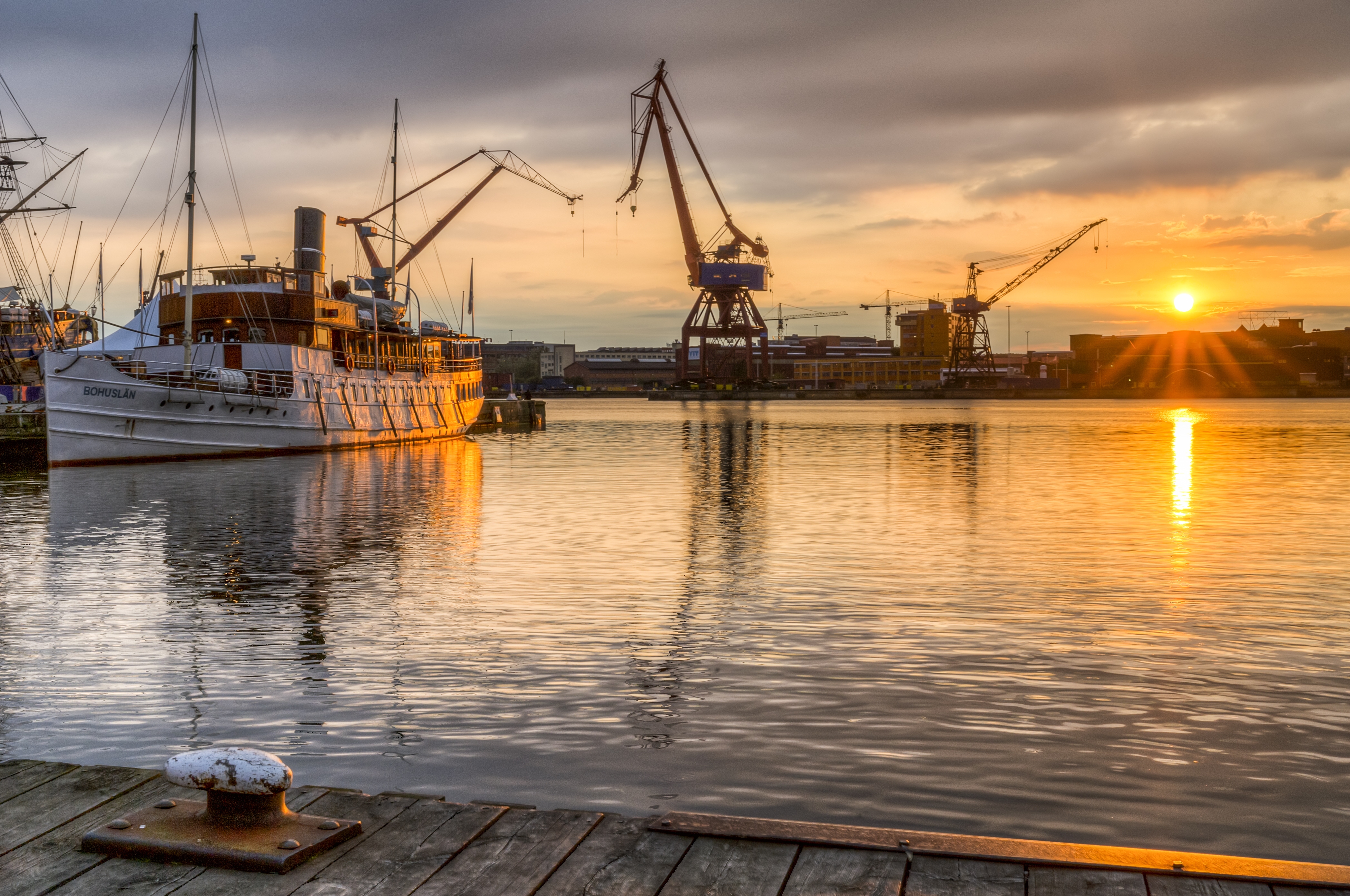 Båt och kranar i Göteborgs hamn i solnedgången