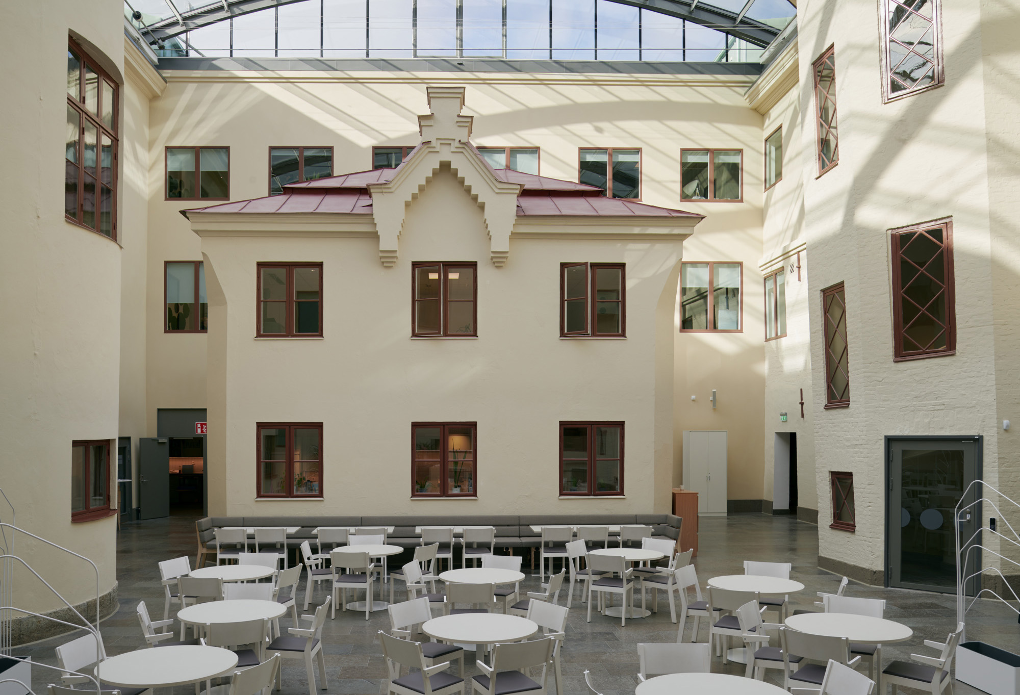 Innergården på Wenngrenska Huset med glastak, bord och stolar.