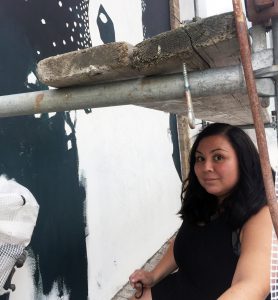 Konstnären Llefen Carrera sitter framför sin muralmålning 
