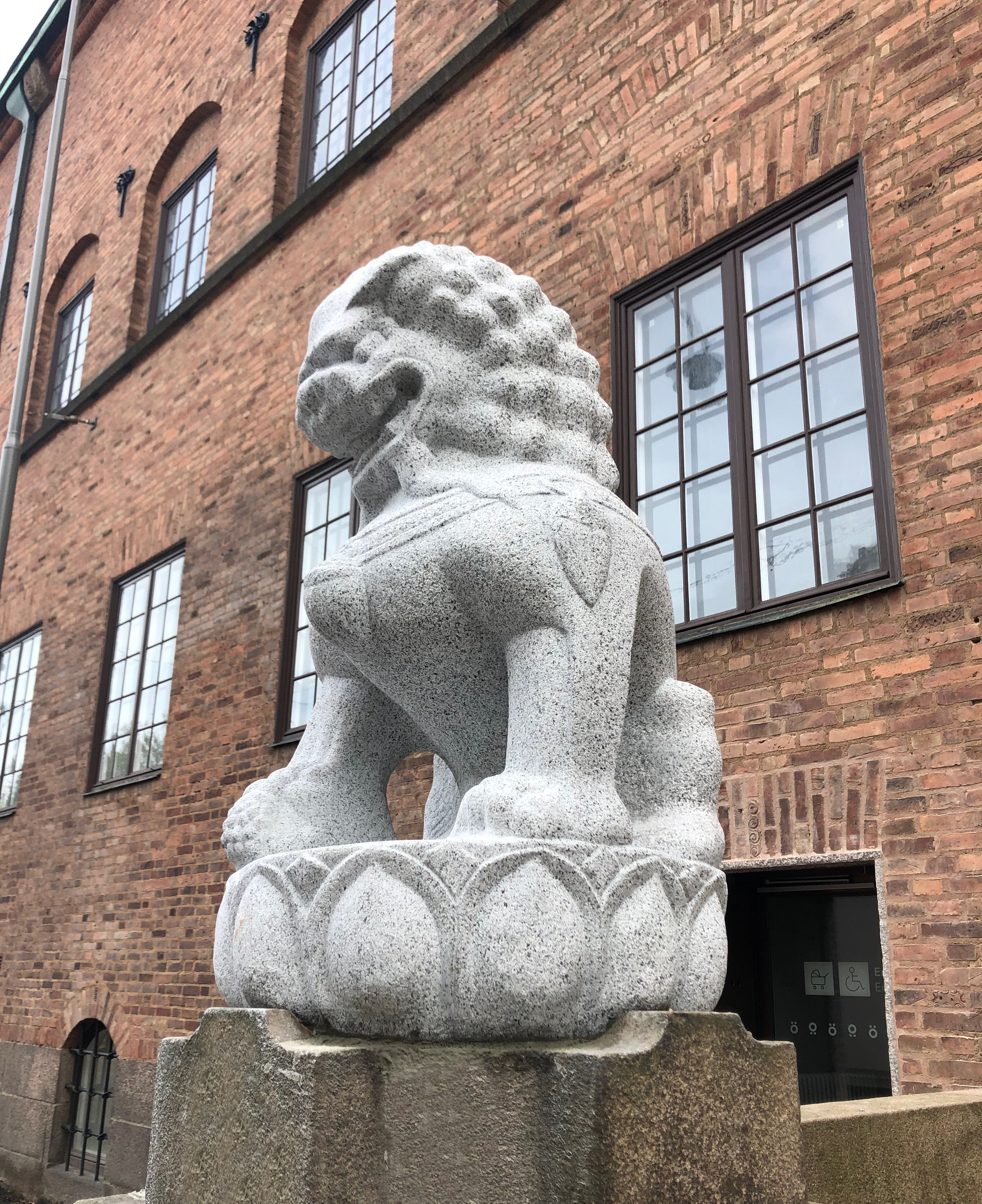 Närbild på lejonskulptur med Röhsska museet i bakgrunden